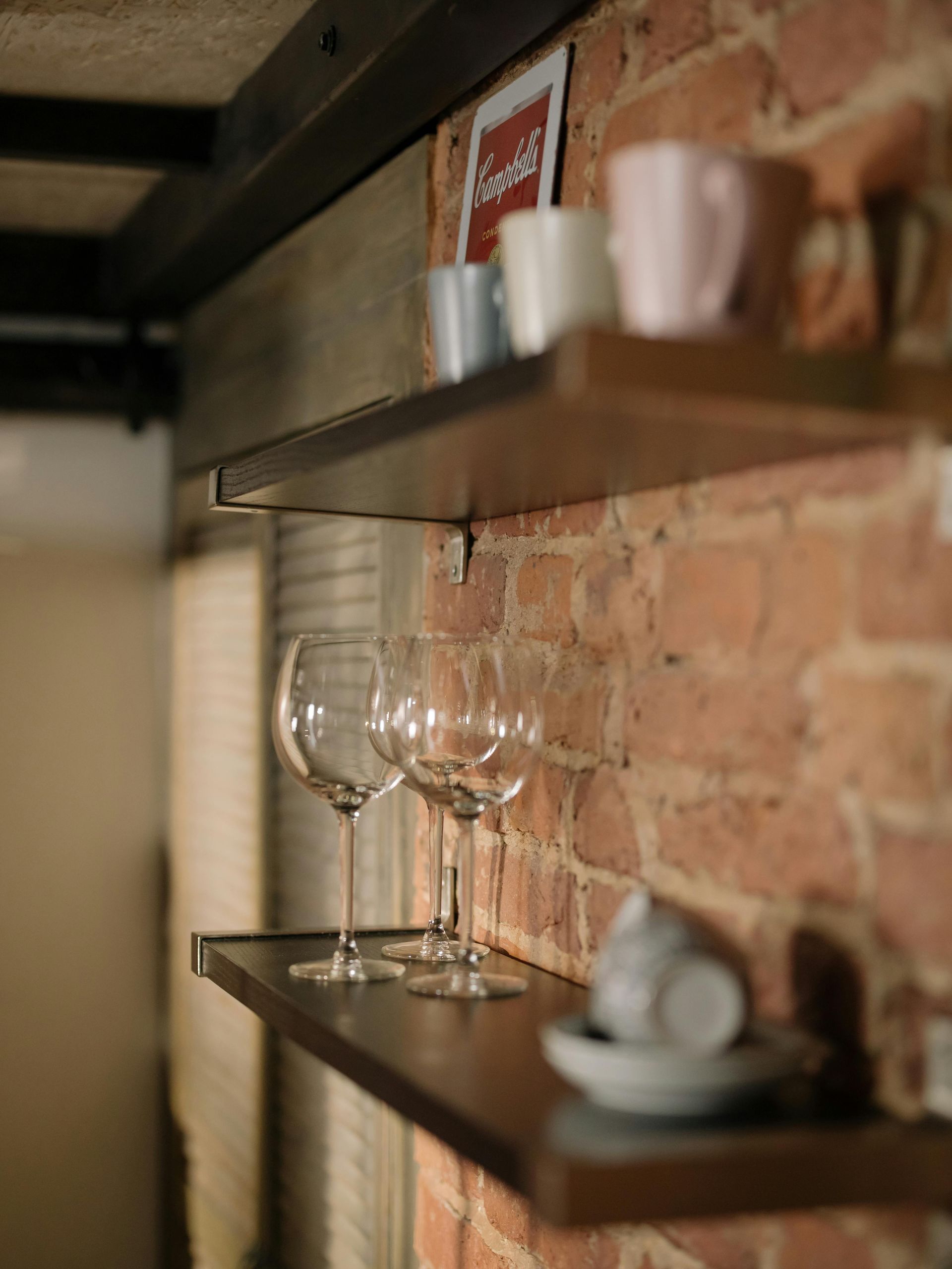 A shelf with blue goggles, a black strap, and a yellow spray bottle against a white wall.
