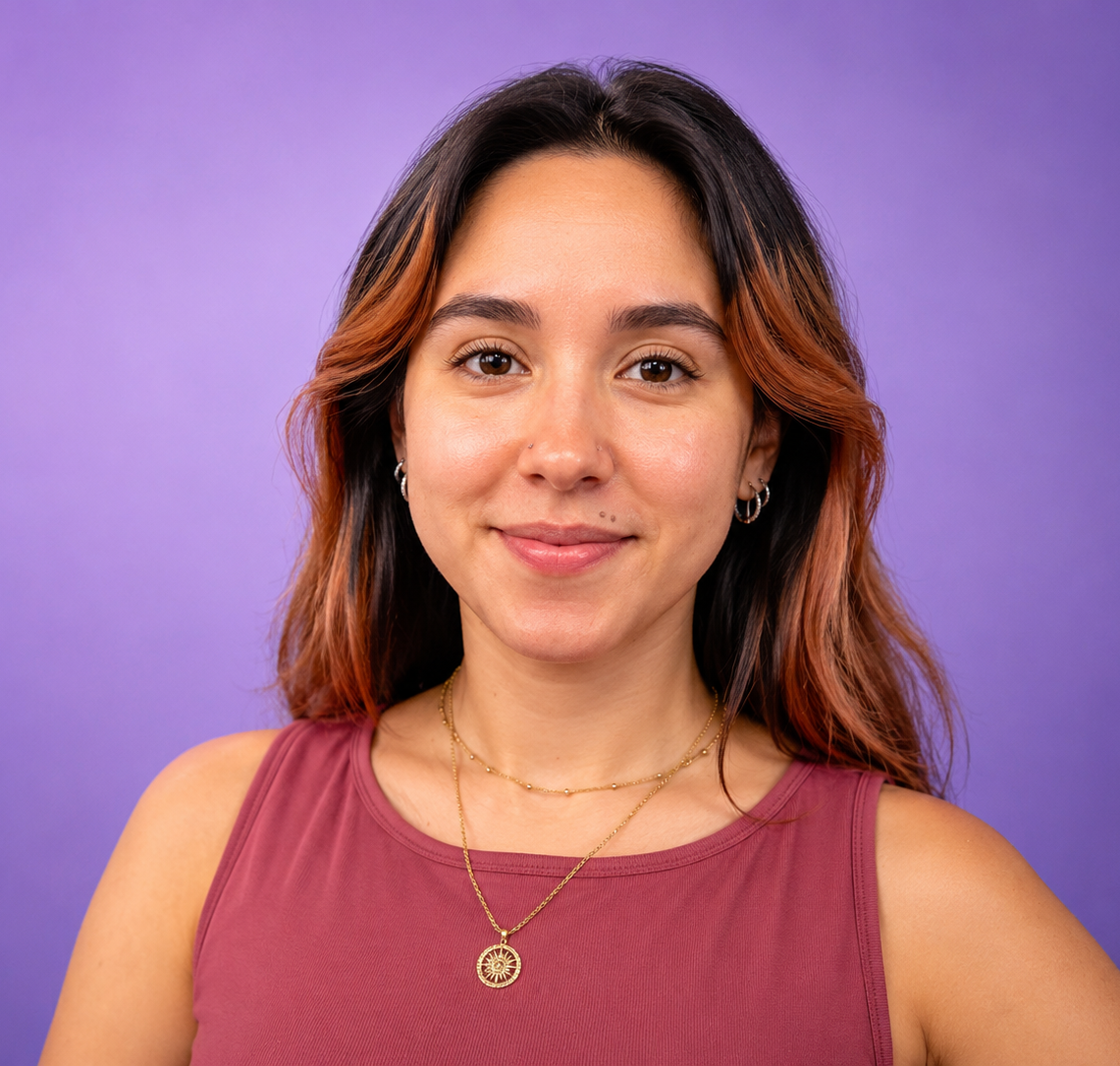 Portrait of a woman smiling against a purple background, wearing a maroon top and gold necklace