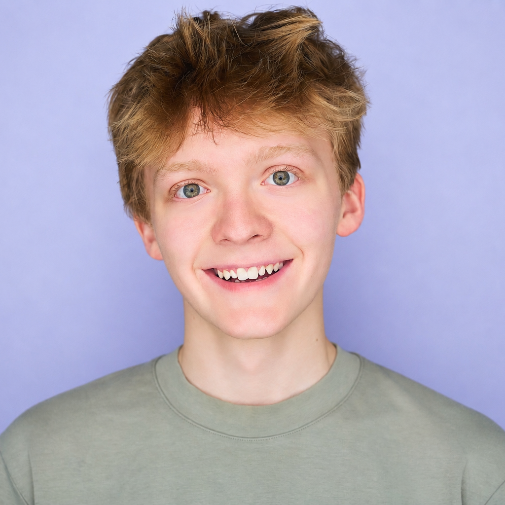 Smiling person with tousled hair in a gray shirt against a light purple background