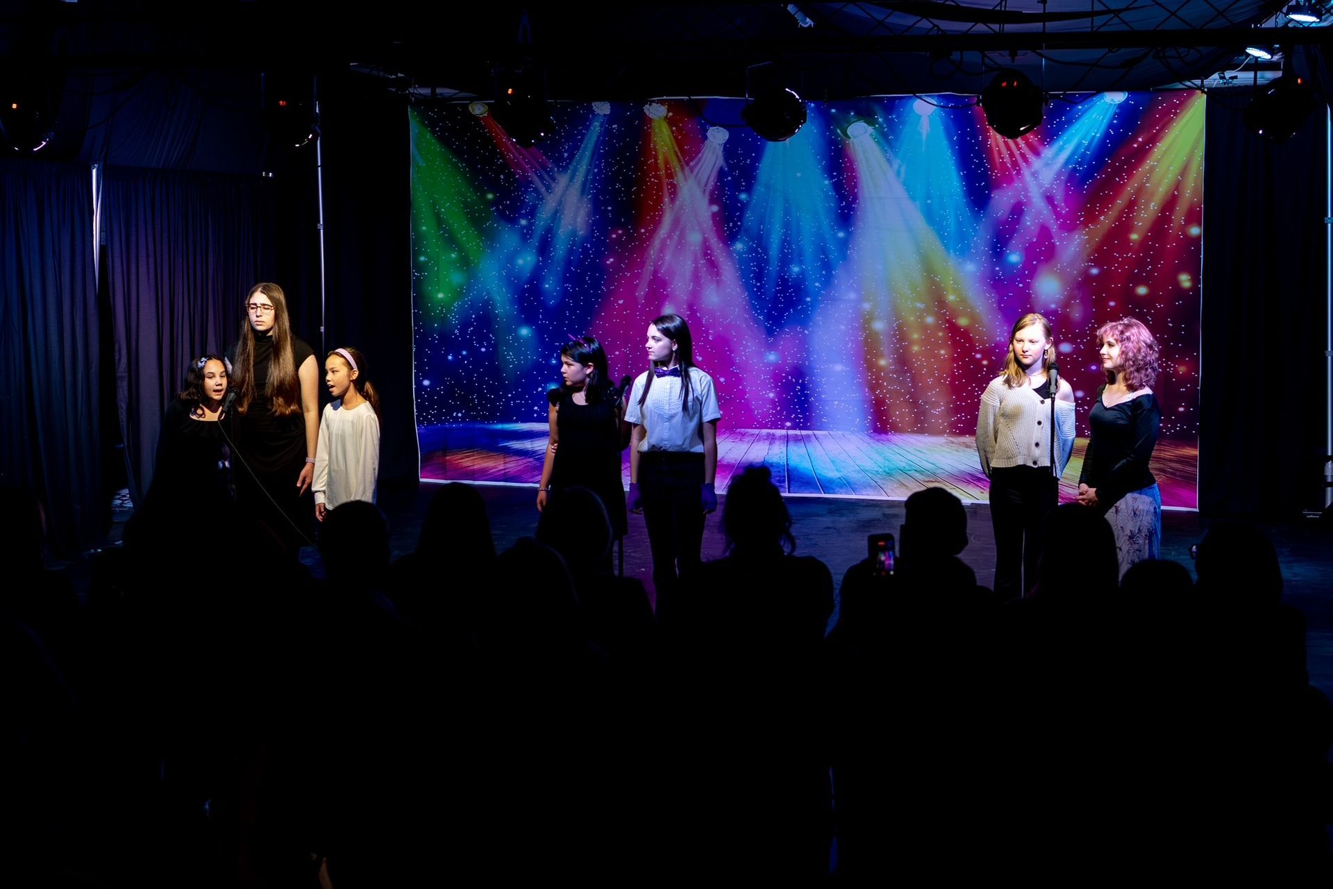 Several performers on stage under colorful lights with a starry backdrop