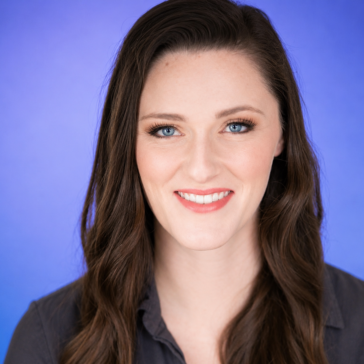 Portrait of a smiling person with dark hair on a blue background