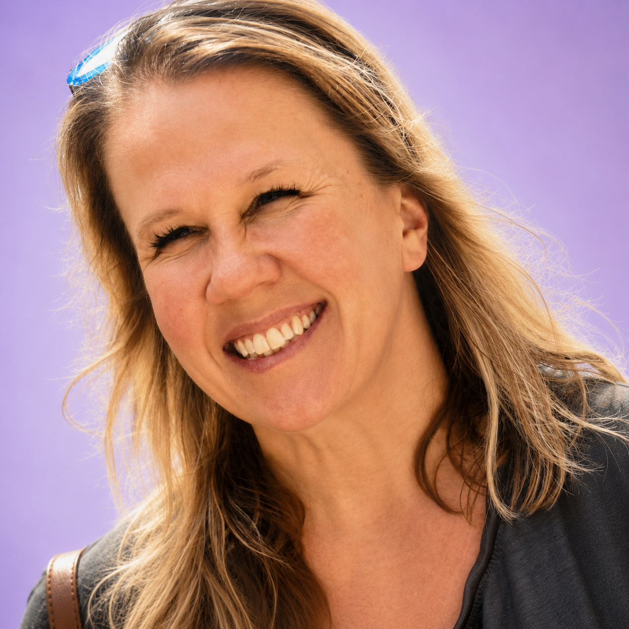 Smiling person with long hair against a purple background