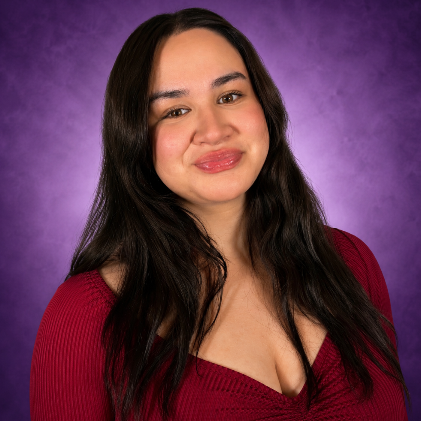 Smiling person with long highlighted hair wearing a white top against a purple background