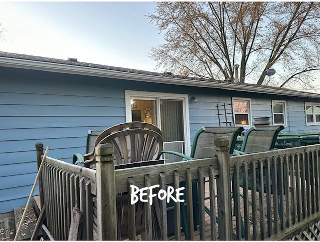 Before view of blue house exterior with wooden fence, patio chairs, and leafless tree