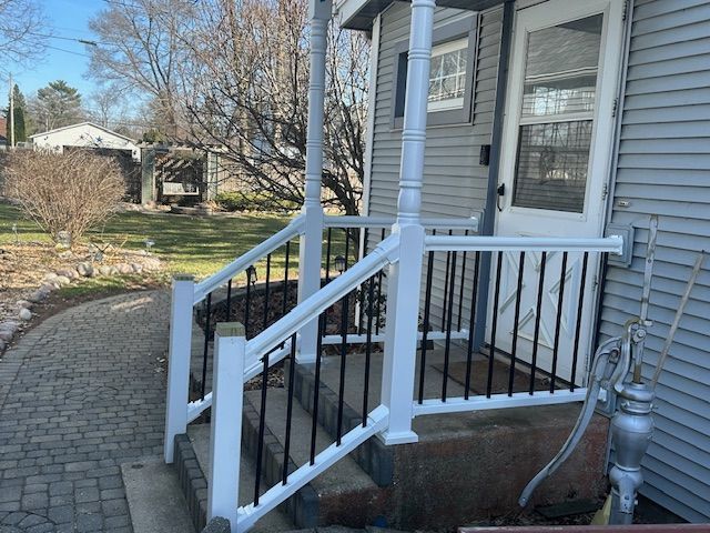 White front porch steps with ramp and railing beside a gray house, leading to a walkway and yard