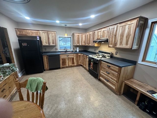 Spacious kitchen with wood cabinets, black appliances, and a window over the sink.