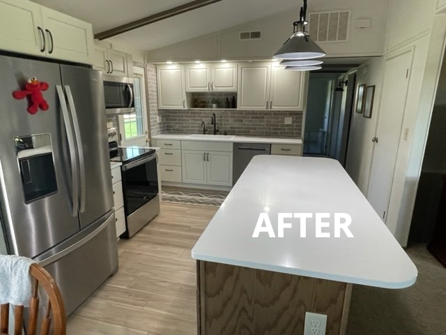 Modern kitchen with stainless steel appliances, white cabinets, and a large white island.