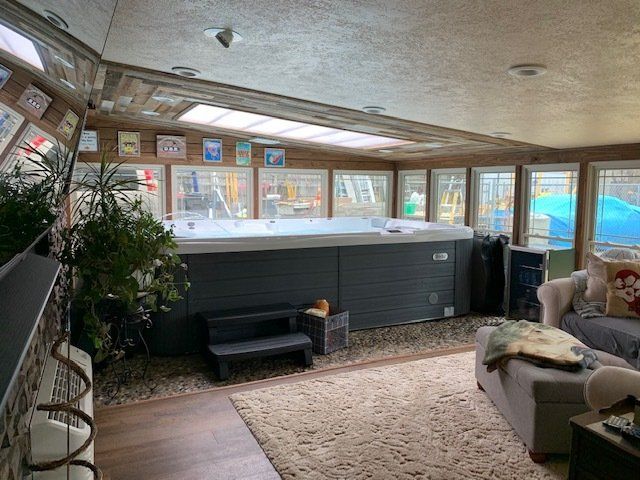 Sunroom with large windows, a dark heater bench, rug, plant, and a sofa by the water view.