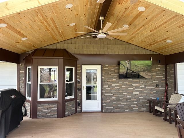 Covered patio with wood ceiling, white door, brick wall, and seating area beneath a ceiling fan