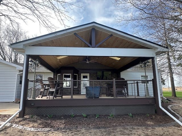 Covered front porch with metal railings, chairs, and white downspouts on a small house.