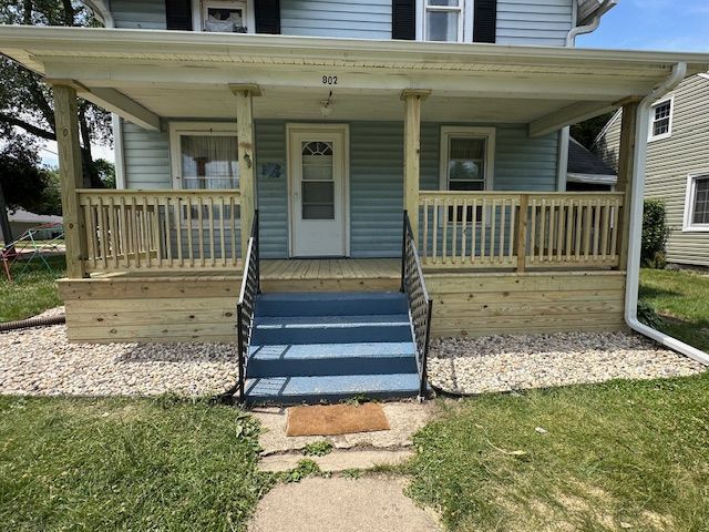 Blue house front porch with ramp, steps, and white railing