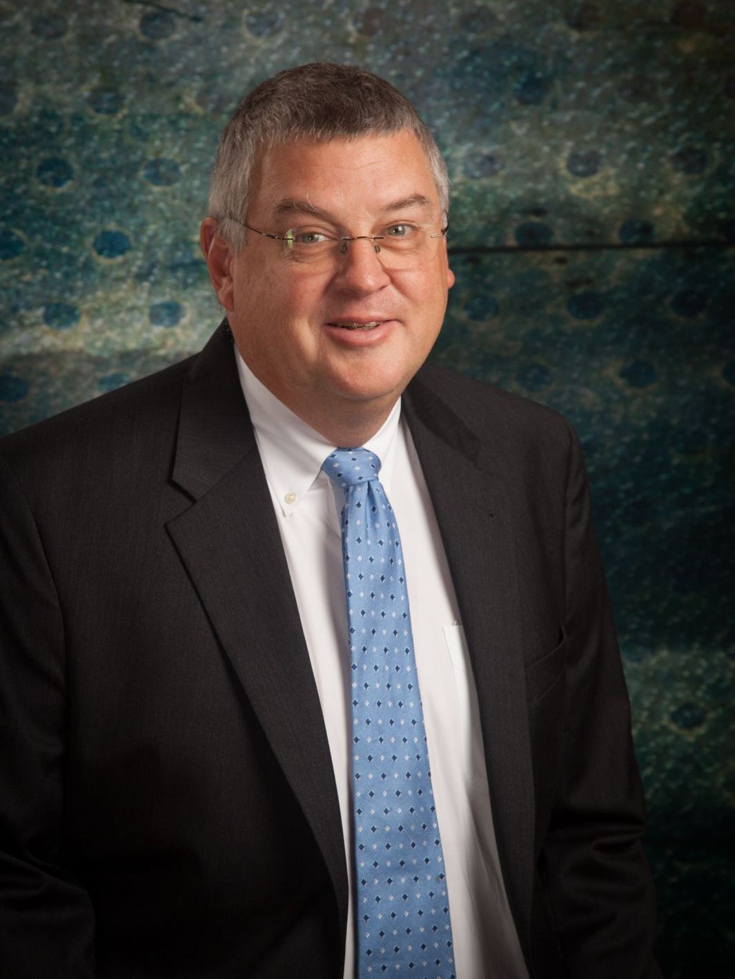 A man in a suit and tie is smiling for the camera.