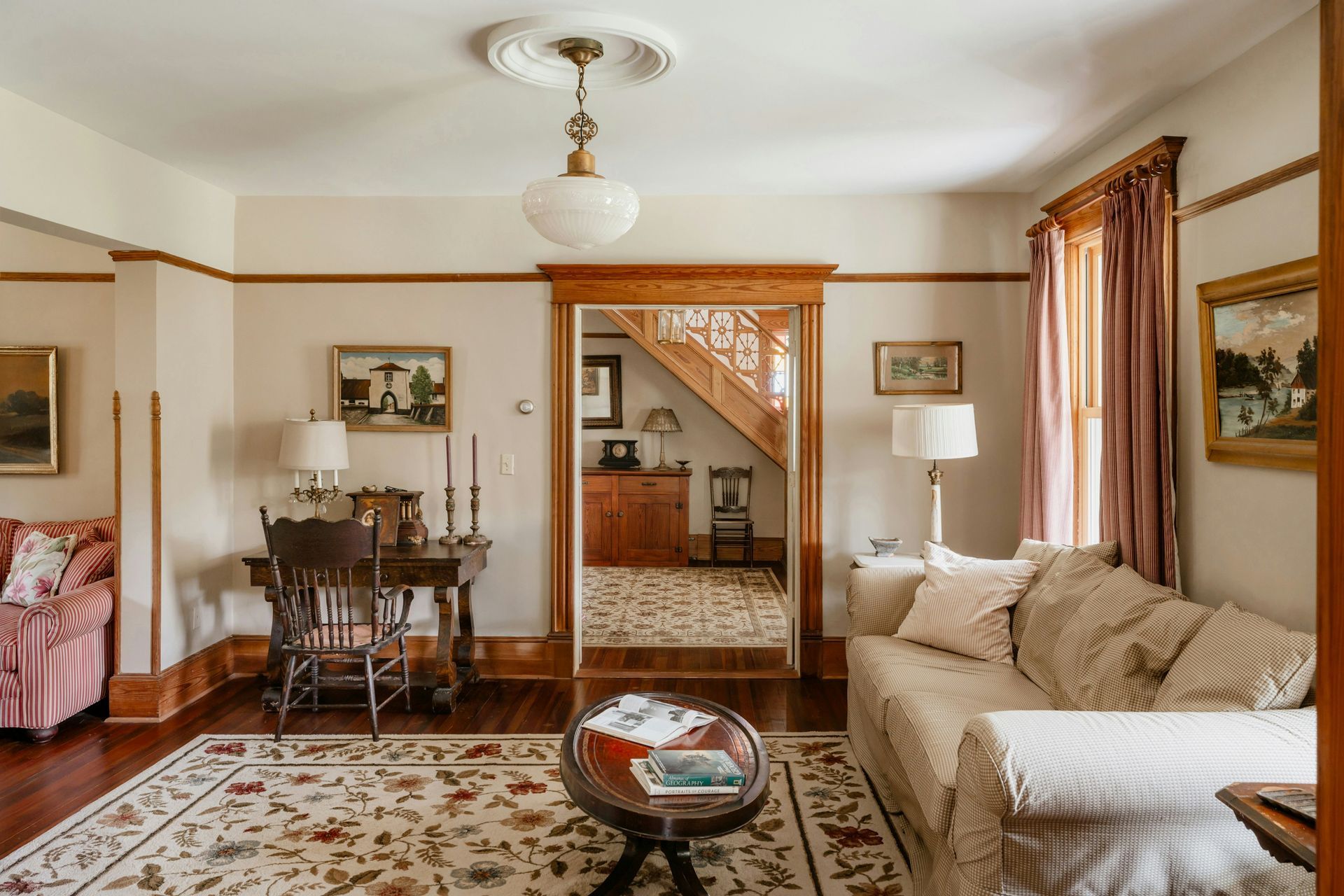 Living room with wood trim, rug, sofa, desk, and view into a stairwell.