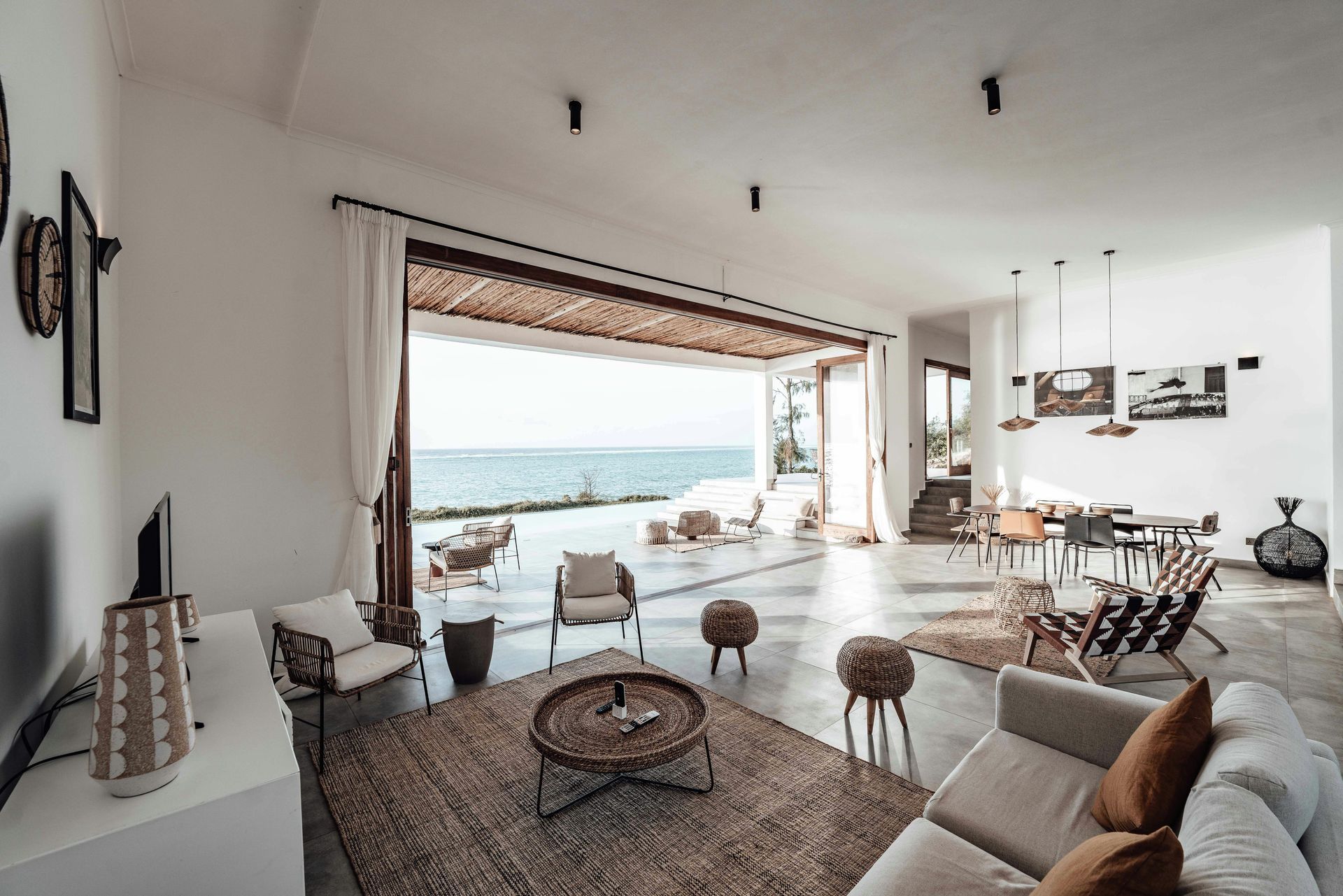 Bright living room with open doors to ocean view. White walls, beige furniture, rug.