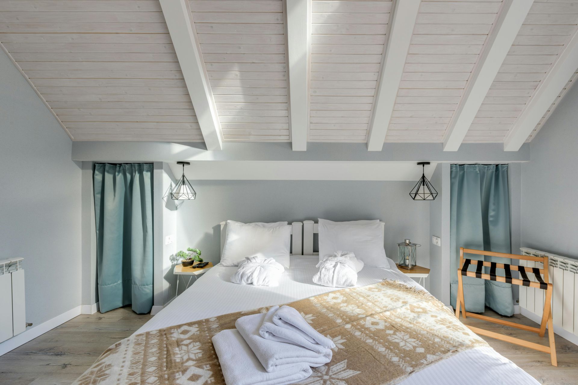 Bedroom with a bed, white ceiling, blue curtains, and two bedside tables.