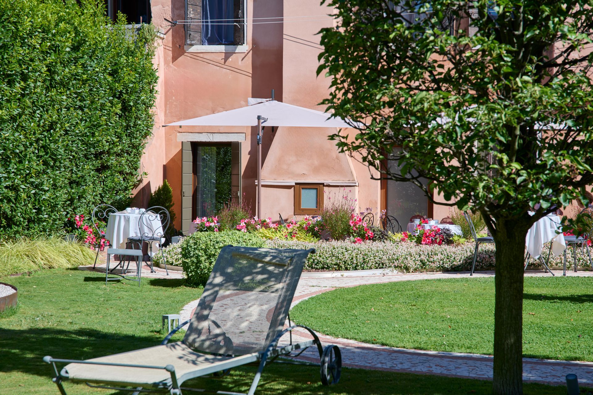A lawn with lawn chairs and umbrellas in front of a house.