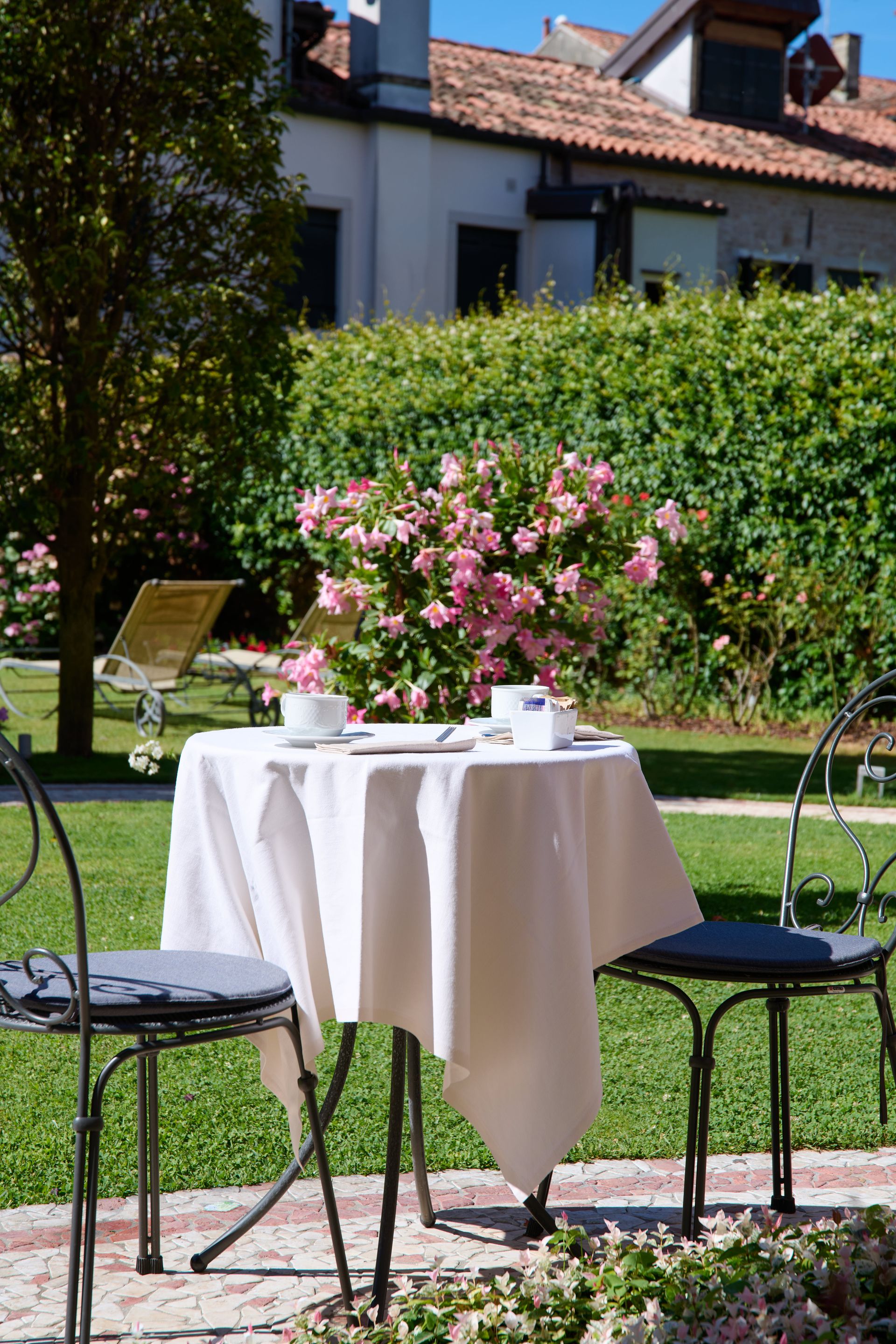 A table and chairs in a garden with flowers in the background