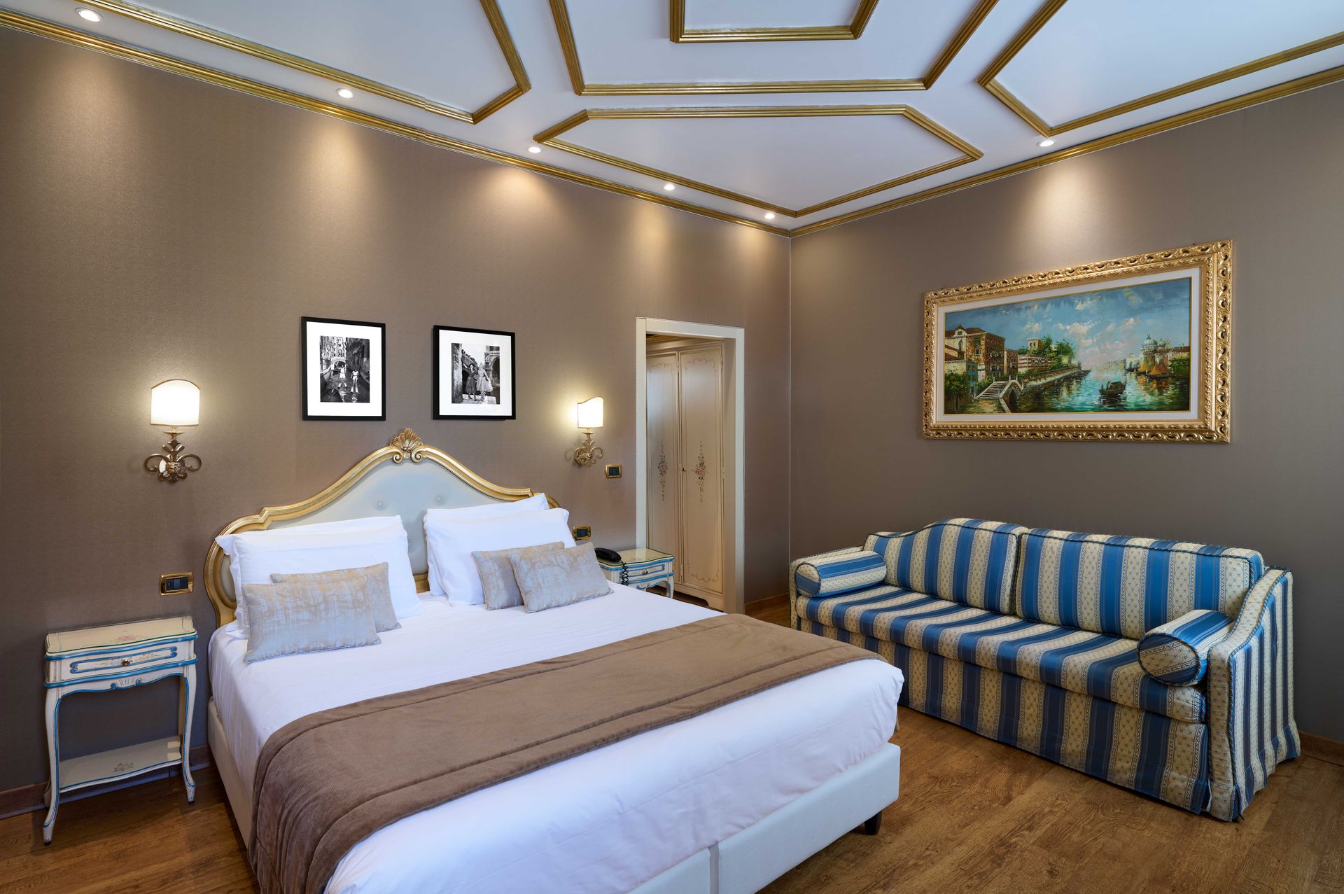 A hotel room with a king size bed and a striped couch.