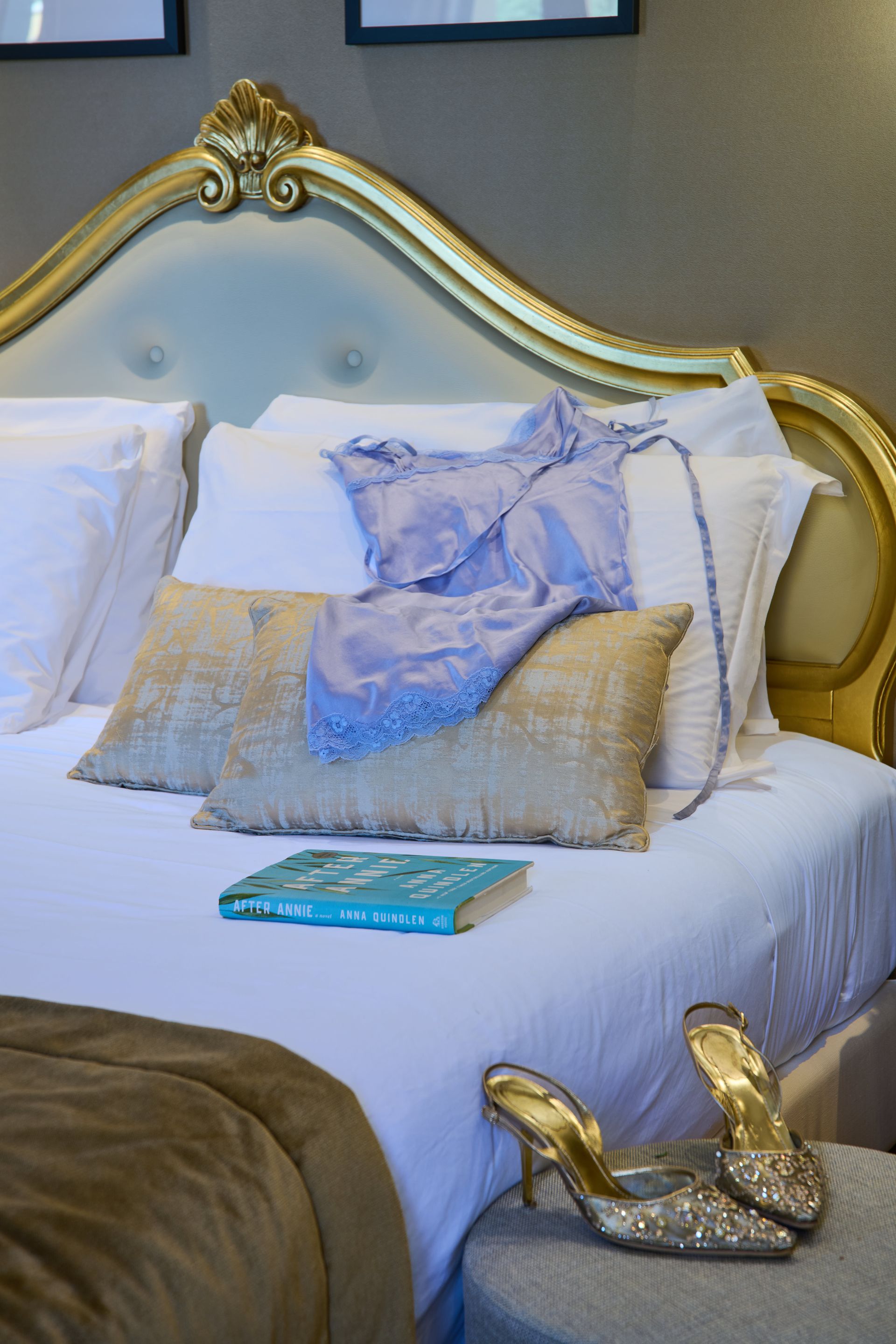 A bed with a book and a pair of shoes on it