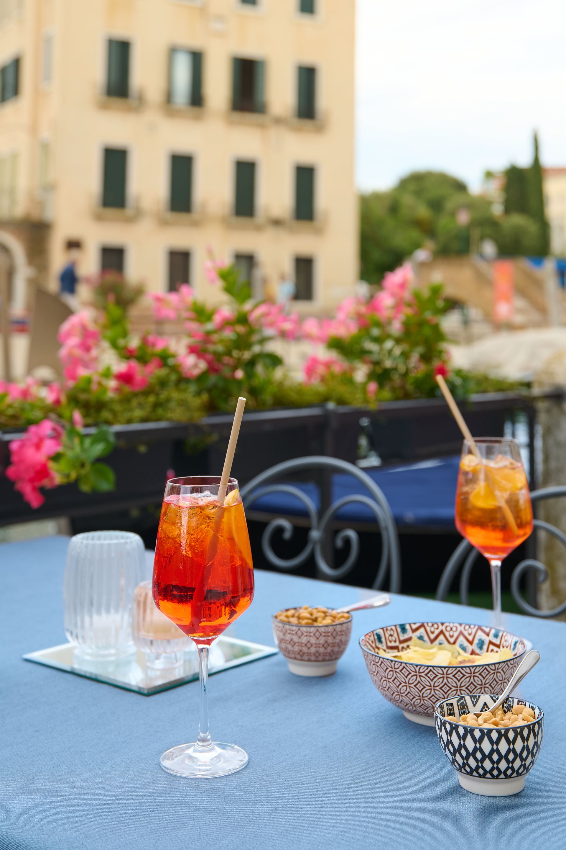 A table with two glasses of wine and bowls of food on it.