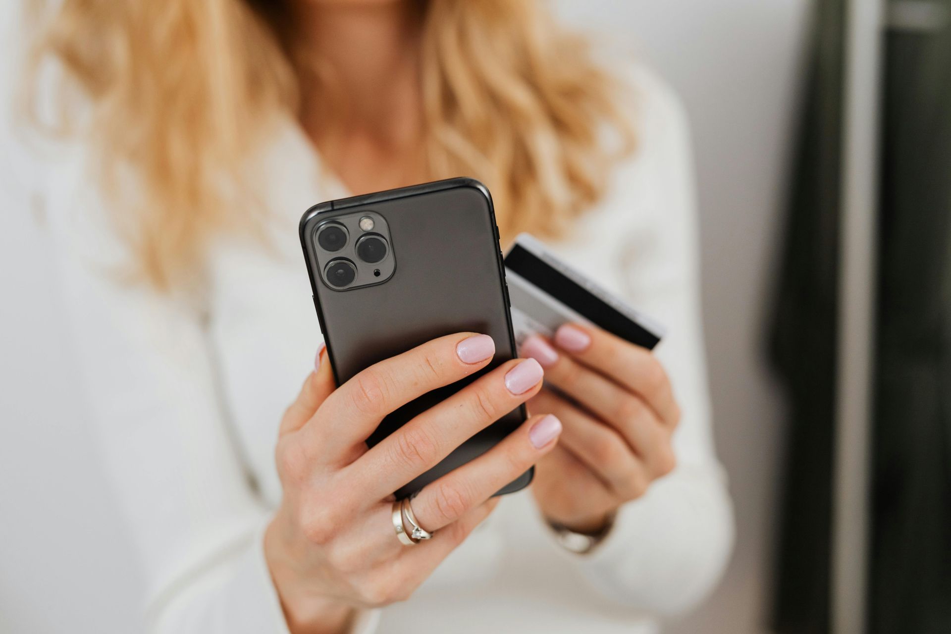 A woman is holding a credit card and a cell phone.