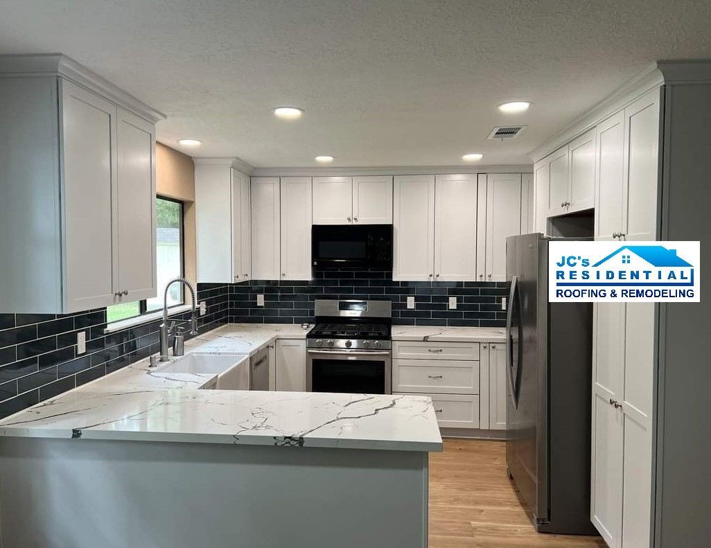 White kitchen cabinets and countertops with a black and gray tiled backsplash.
