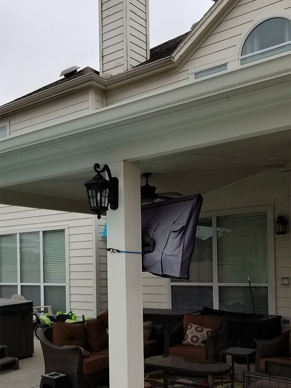Covered outdoor patio with a TV, seating, and a decorative lantern.