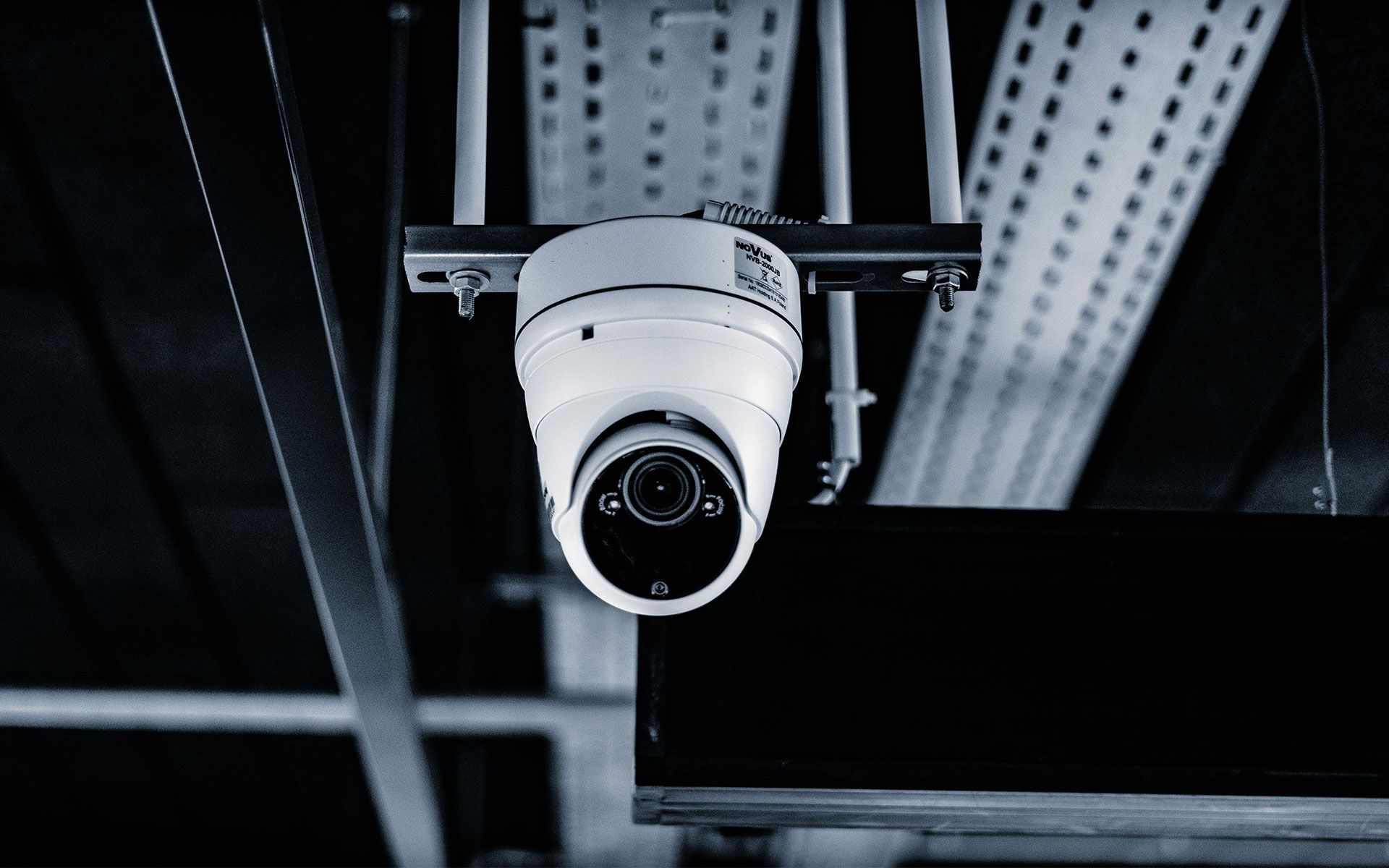 A security camera is hanging from the ceiling of a building.