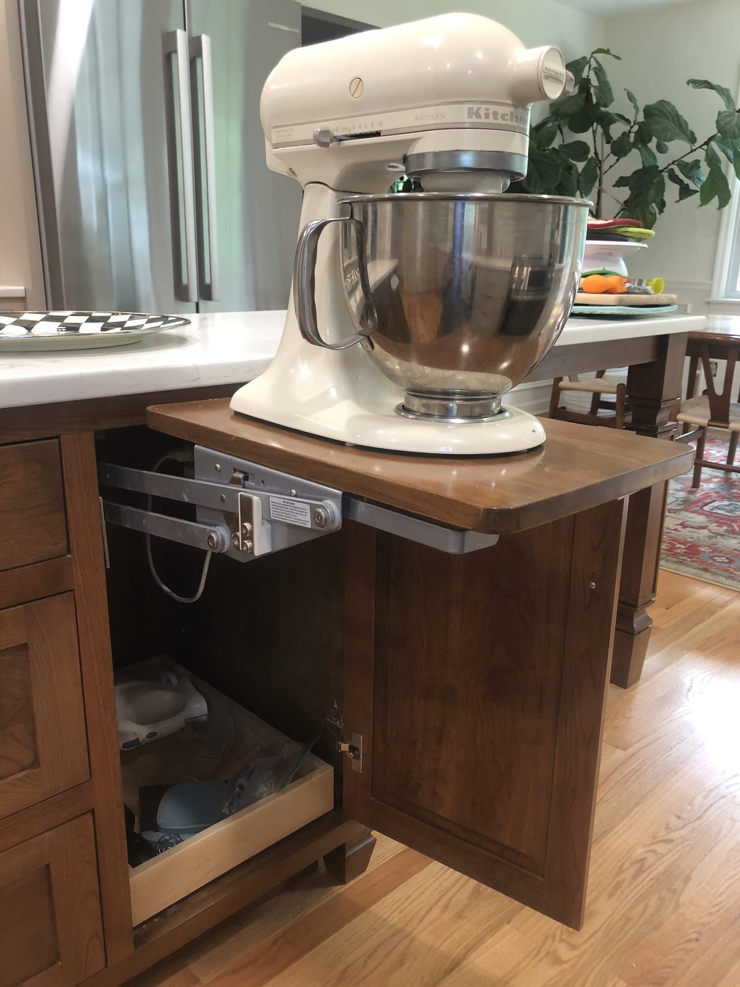 White stand mixer on a countertop beside an open cabinet in a kitchen