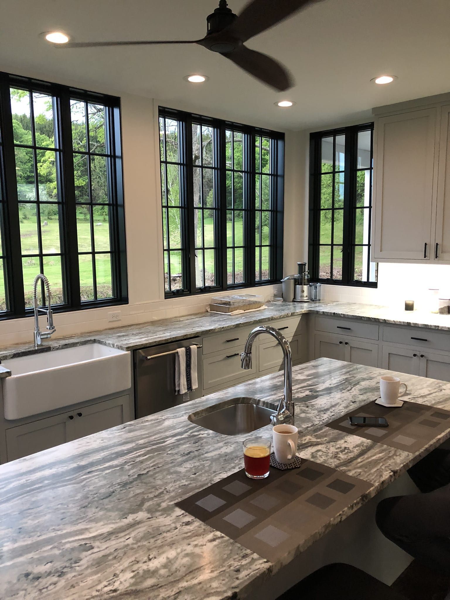 Partially renovated kitchen with cabinets, island, stove, window, and unfinished walls