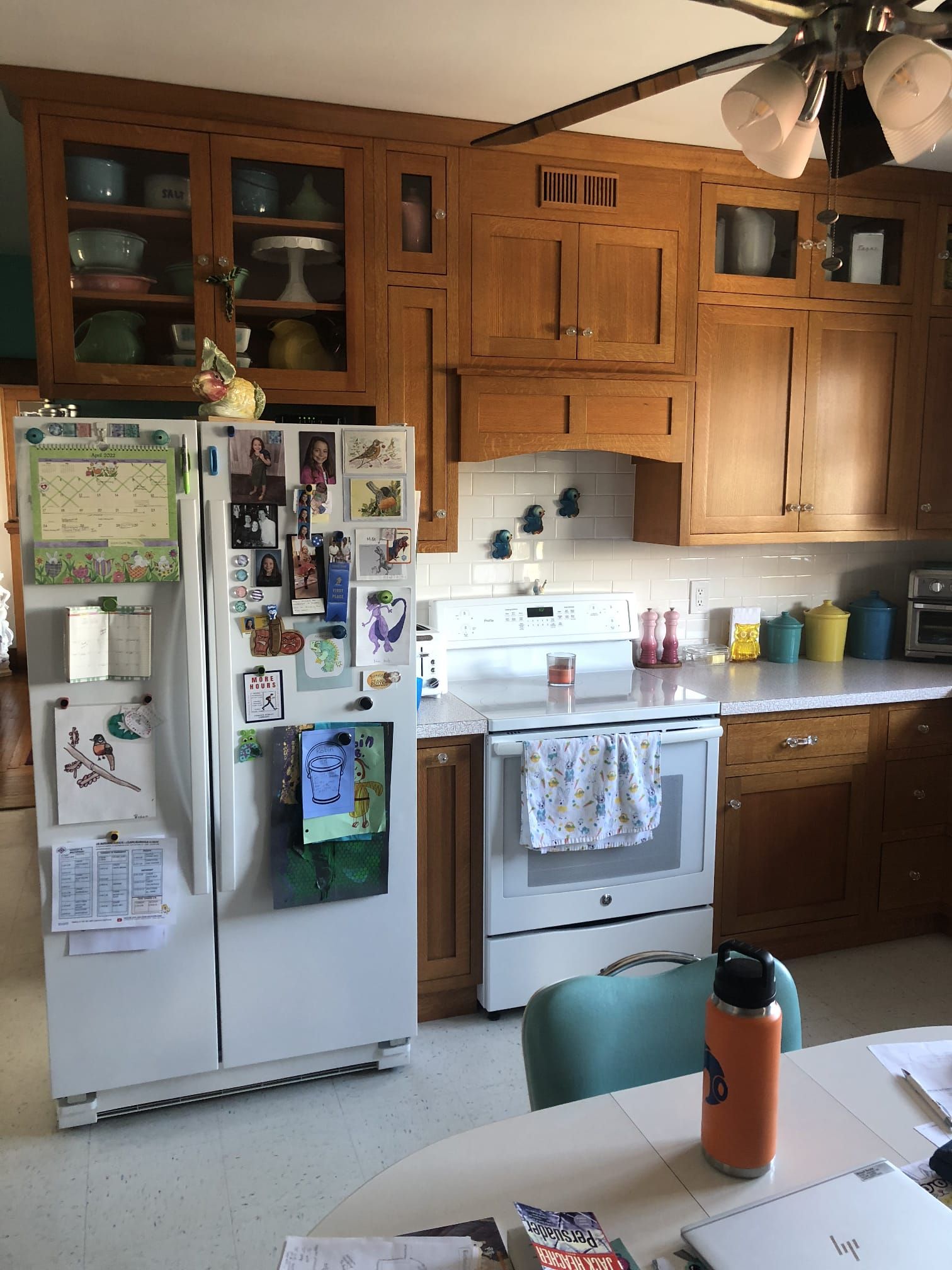 Bright kitchen with white cabinets, granite island, stainless stove, and tiled floor