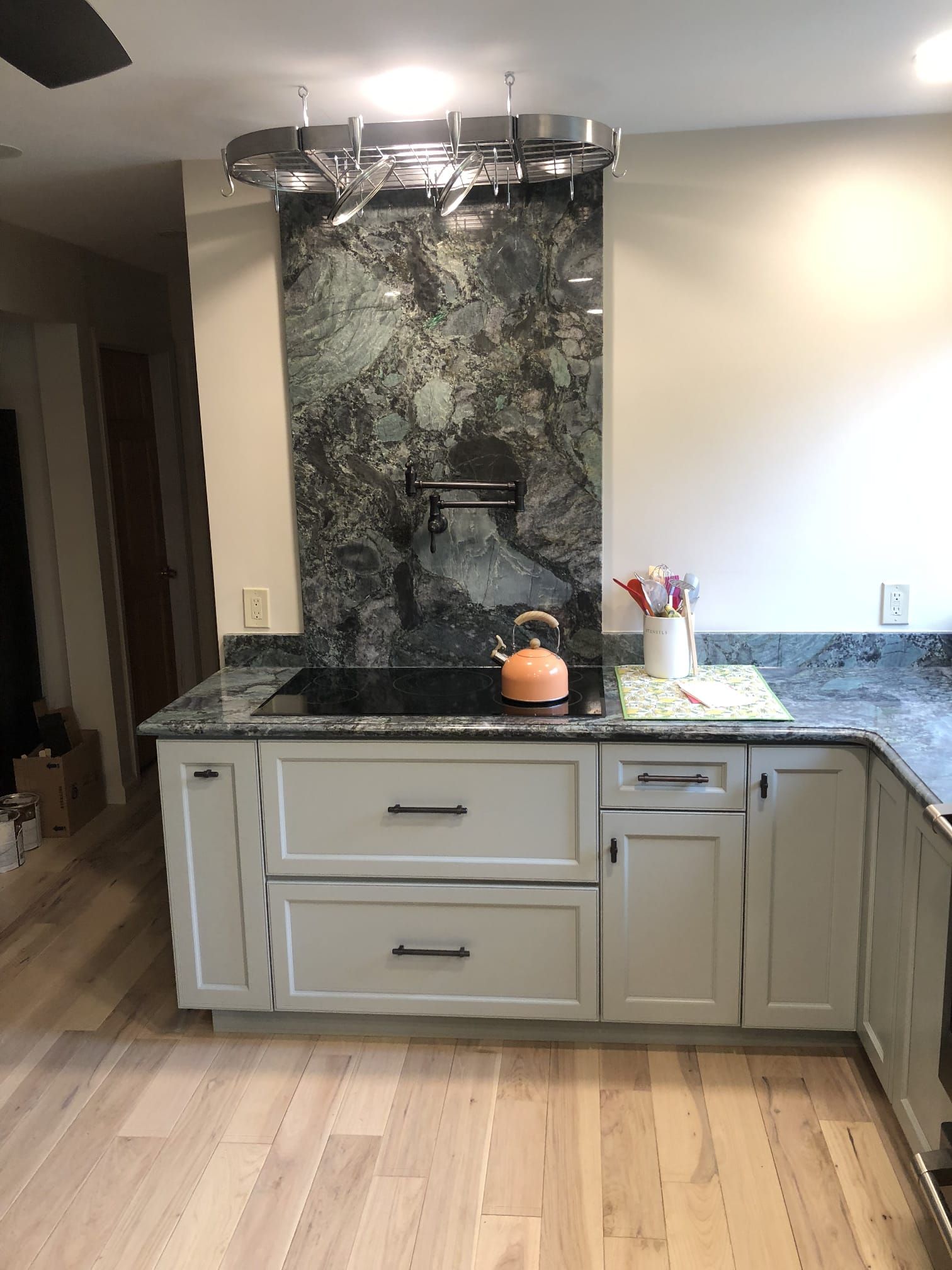 Partially renovated kitchen with cabinets, island, stove, window, and unfinished walls
