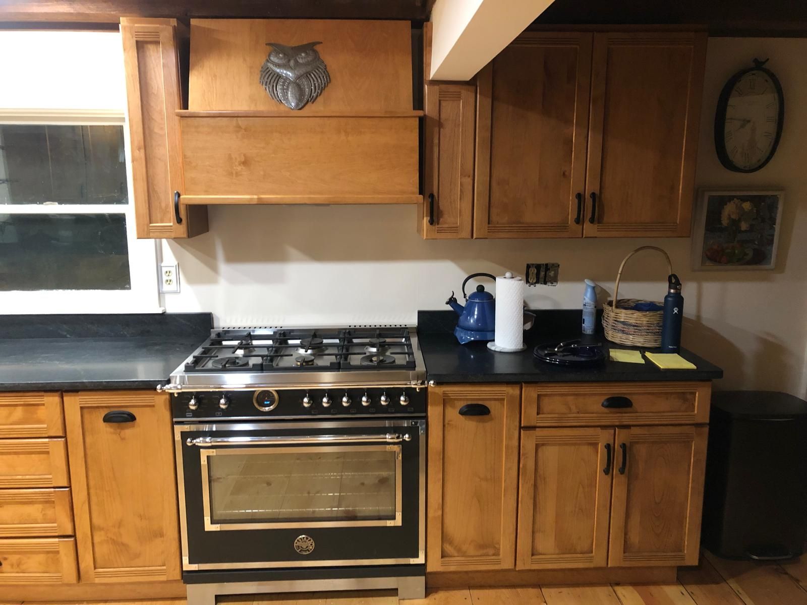 Wooden kitchen with gas stove, cabinets, countertop appliances, and a window above the sink.