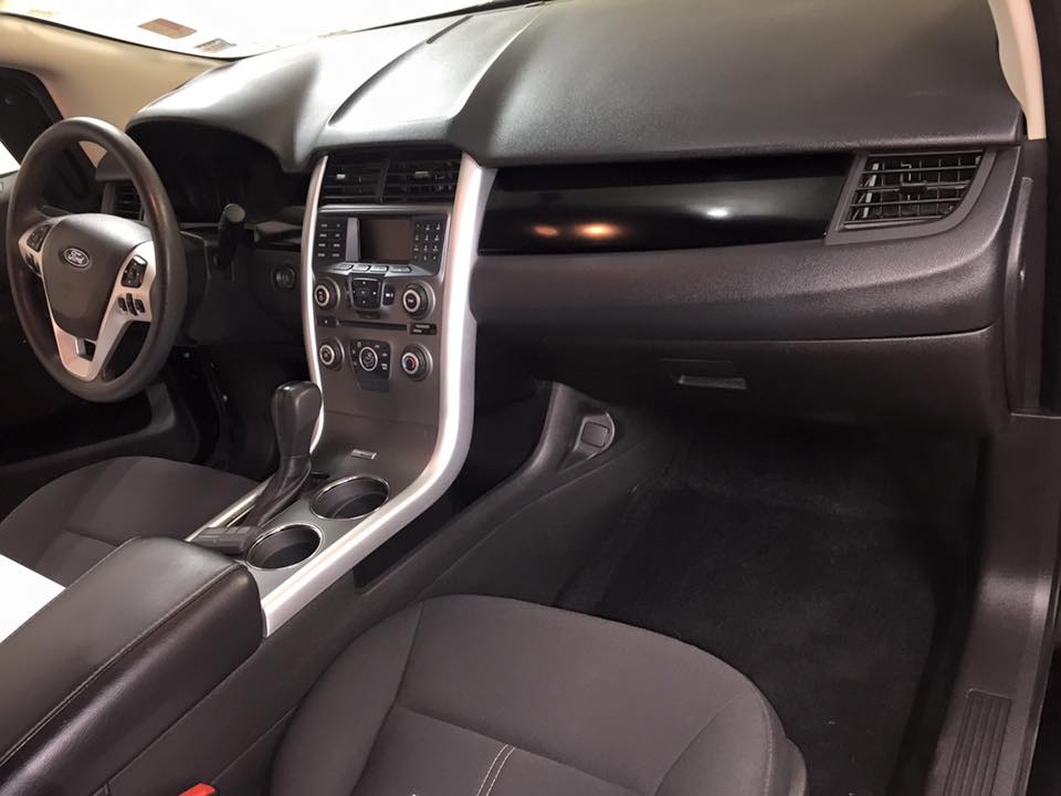 Car interior with black seats, silver center console, dashboard, and steering wheel.