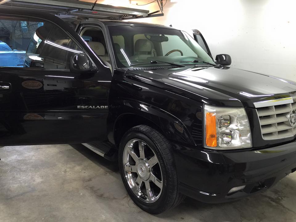 Black Cadillac SUV parked in a garage, front-left view.