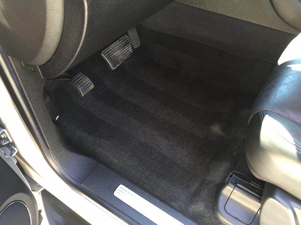 Car interior with black carpeted rear floor, seats, and a silver door sill trim
