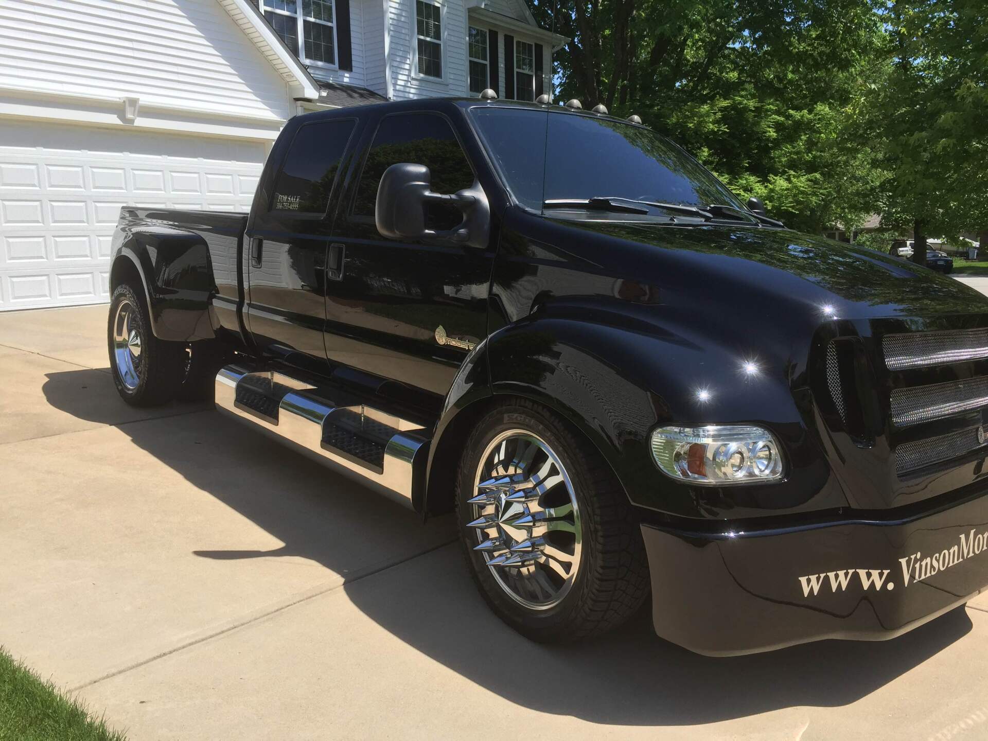 Black lifted pickup truck parked in a driveway beside a house