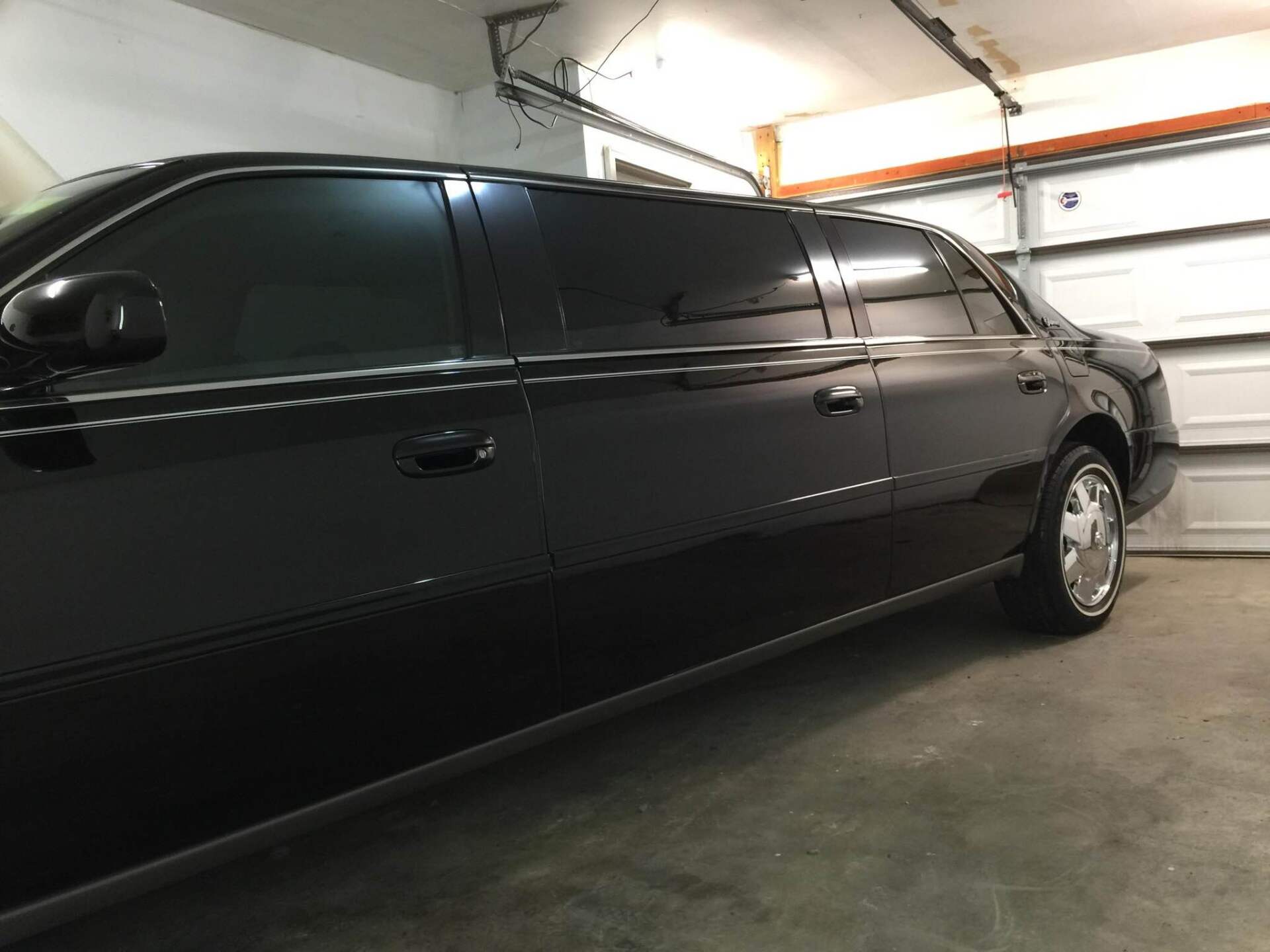 Black sedan parked inside a garage with the door open