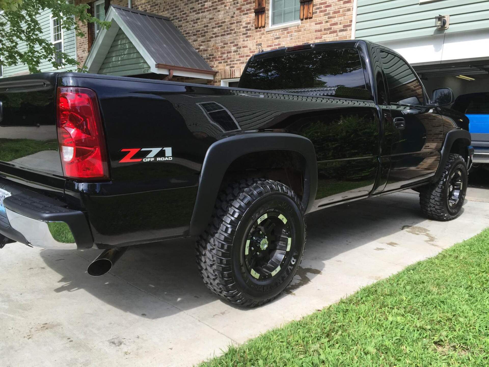 Black Chevrolet Silverado Z71 pickup truck parked in a driveway beside a brick house