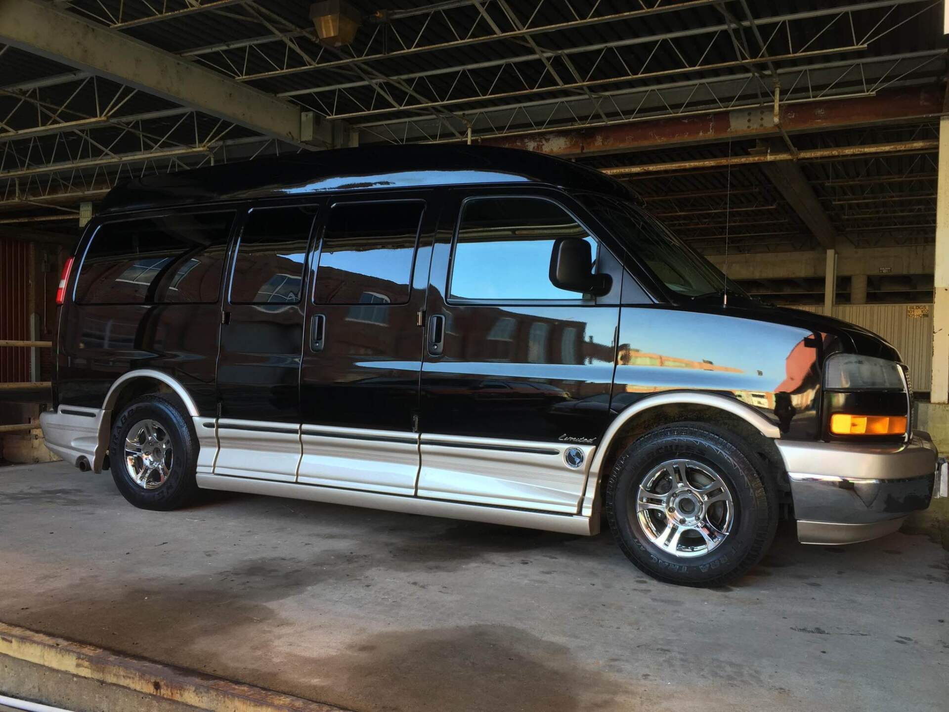 Dark maroon and silver passenger van parked inside an industrial garage