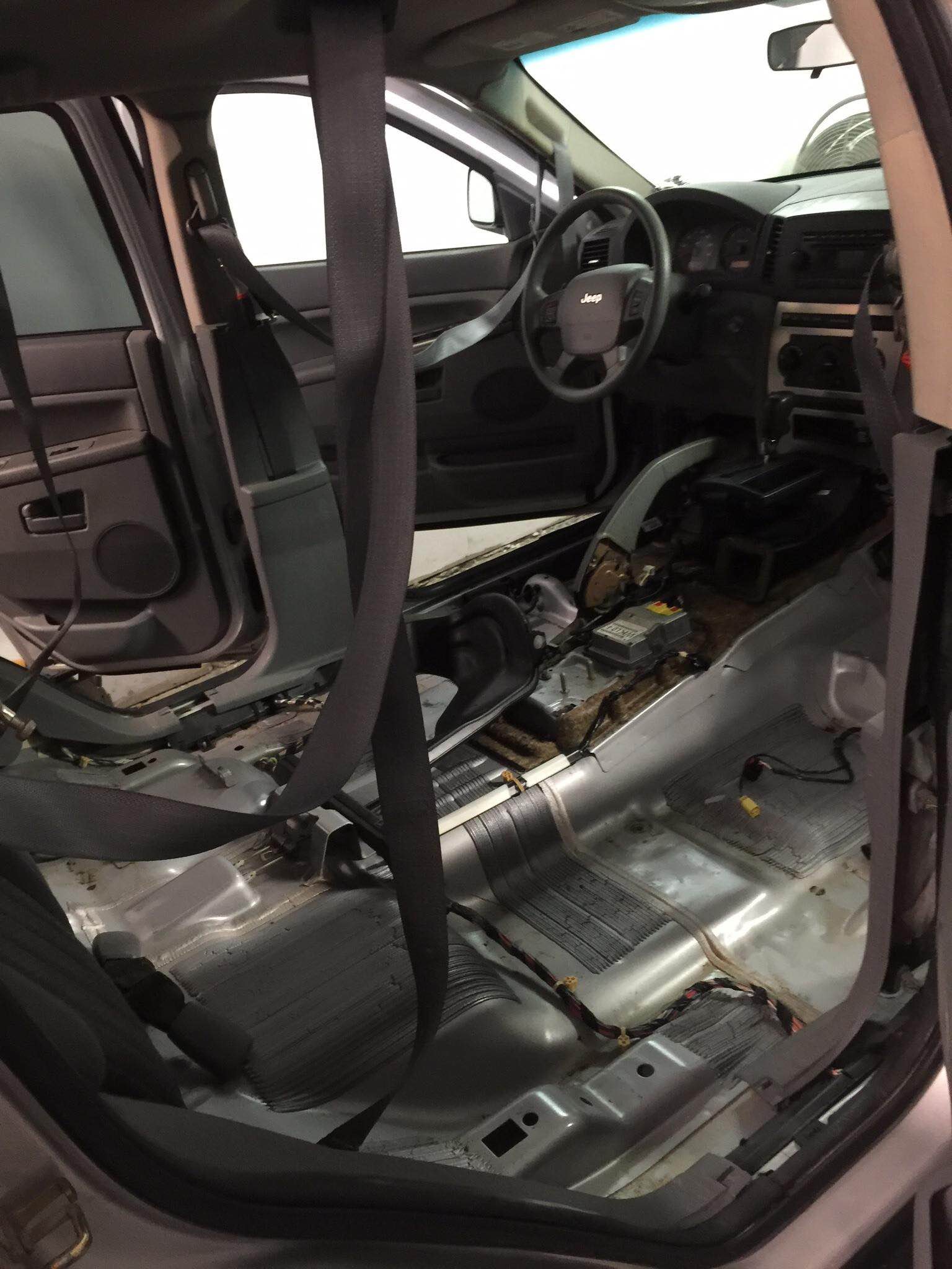 Car interior stripped to bare metal floor with exposed wiring and removed seats.