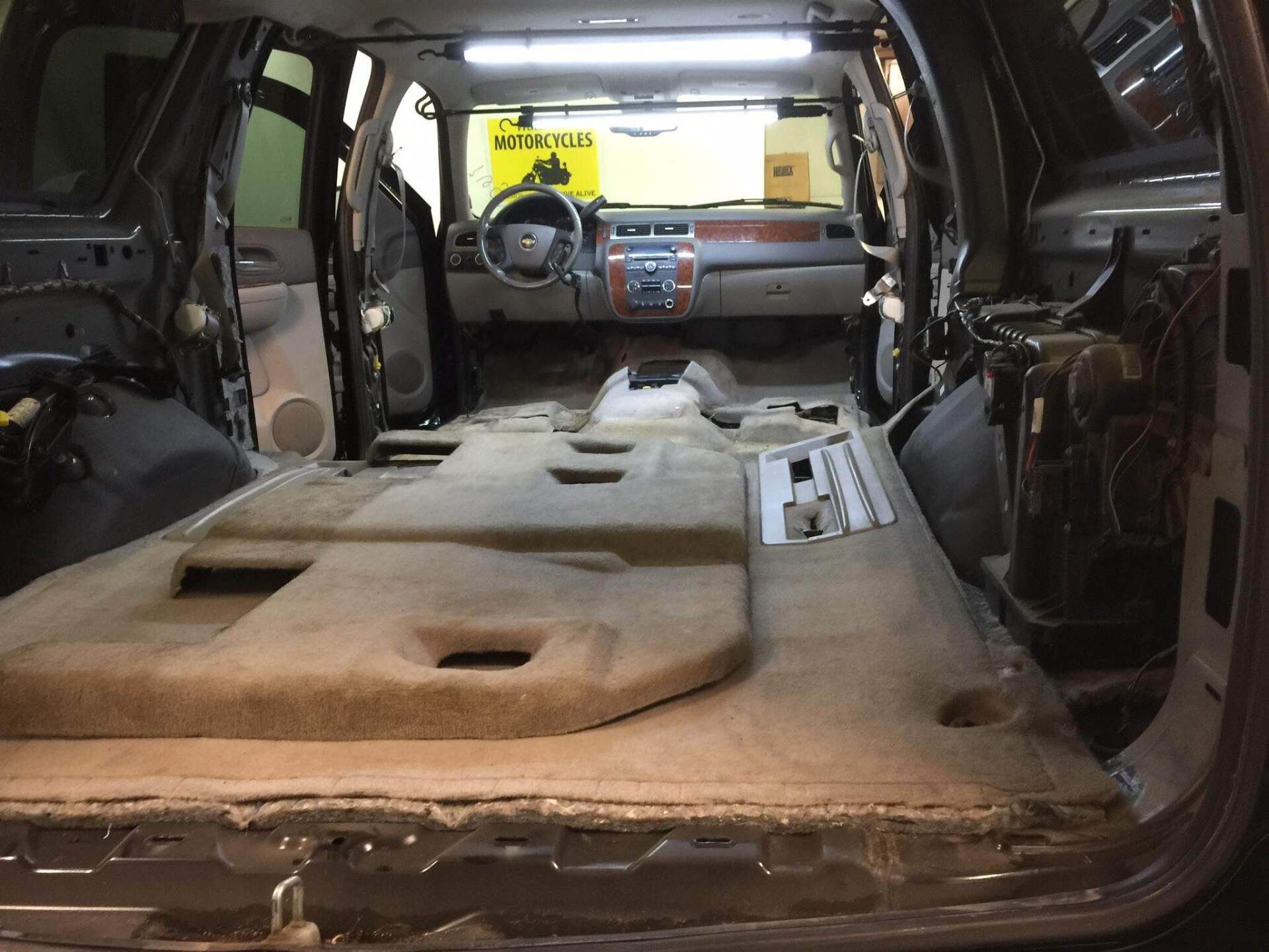 Interior of a stripped vehicle with folded rear seats and exposed cargo area under repair