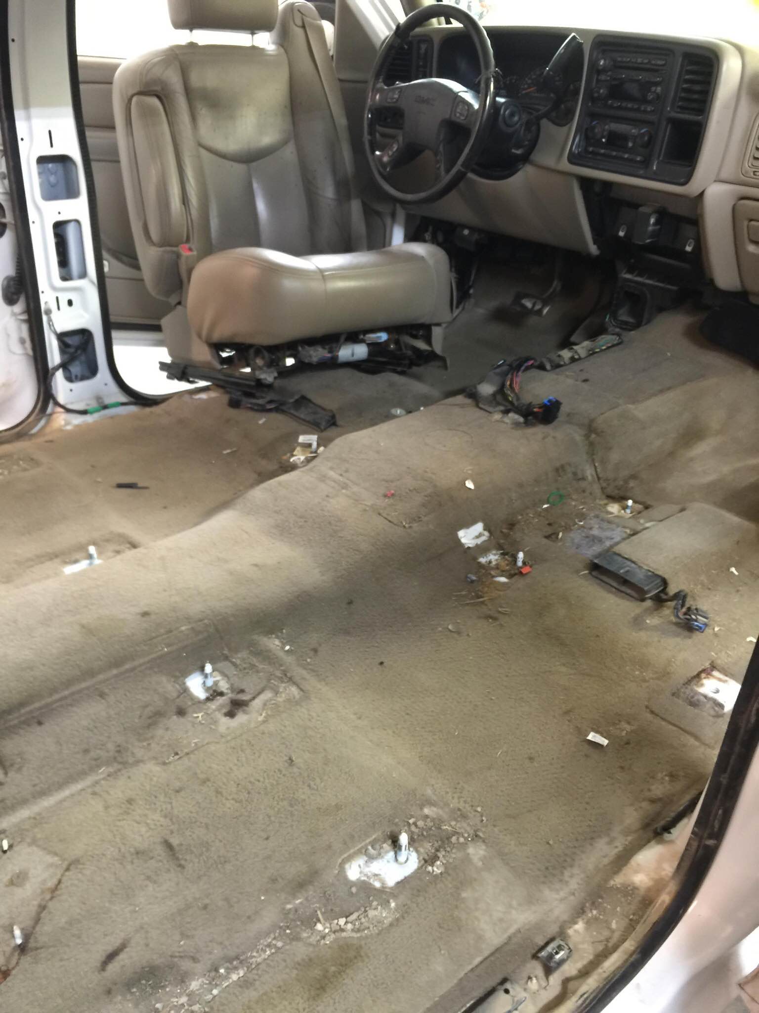 Dirty vehicle interior with gray seats, bare floor, and dashboard visible.