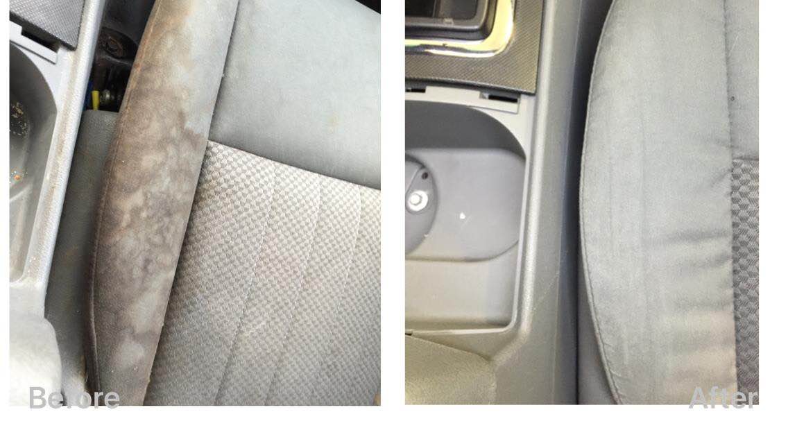 Close-up of gray car seat upholstery showing fabric damage and wear near the center console.
