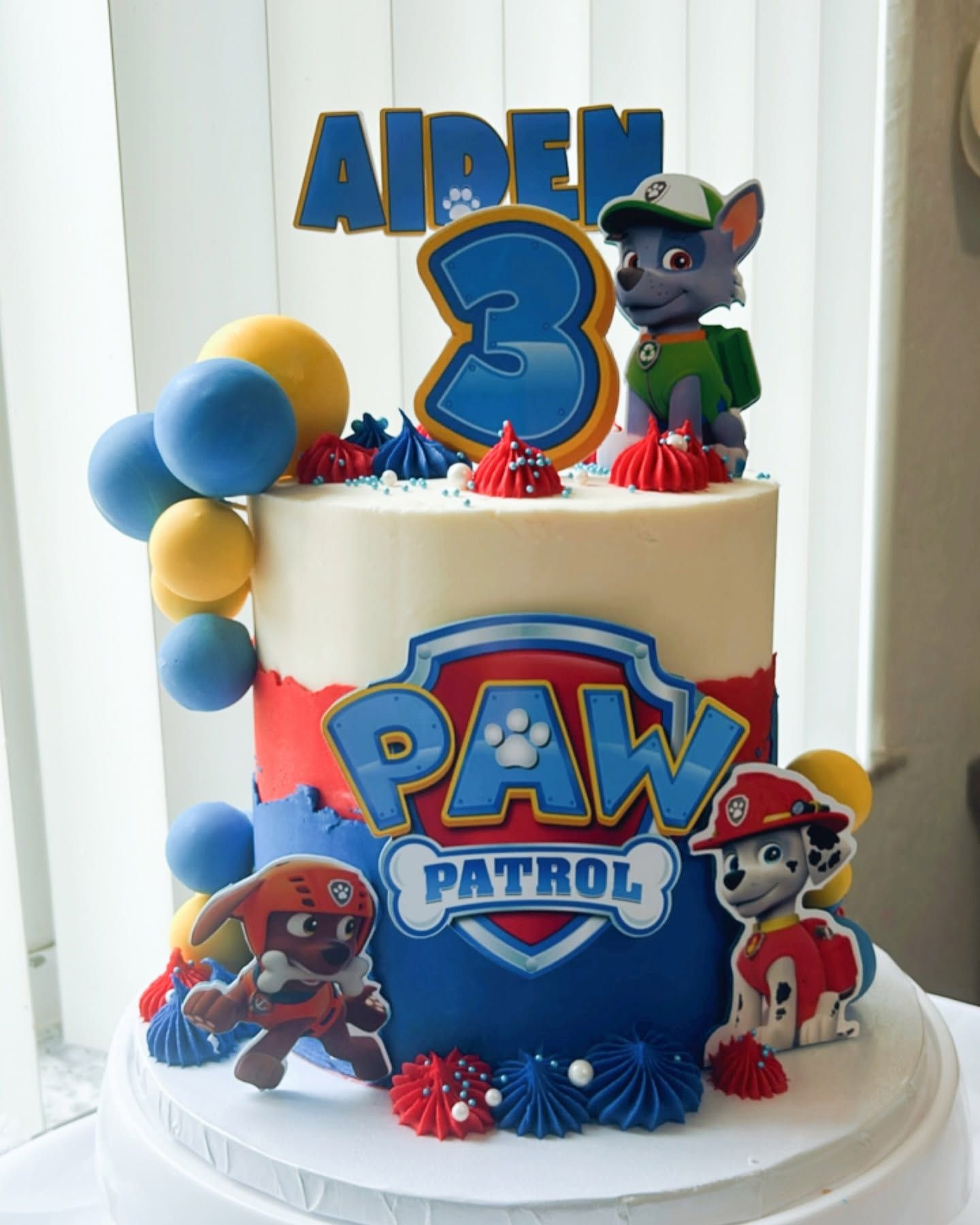 A cake with paw patrol characters on it is on a table.