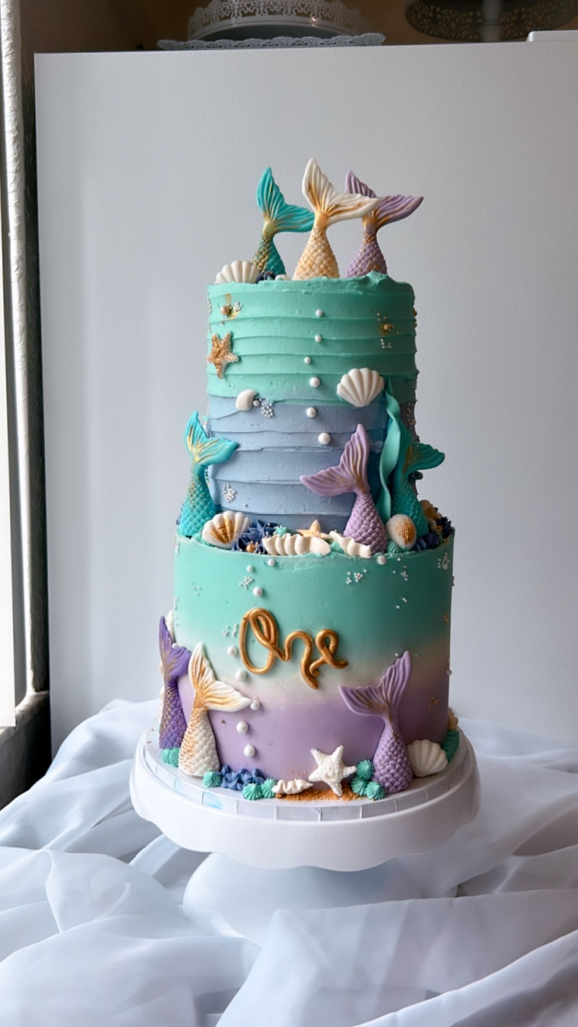 A mermaid cake is sitting on top of a white table.