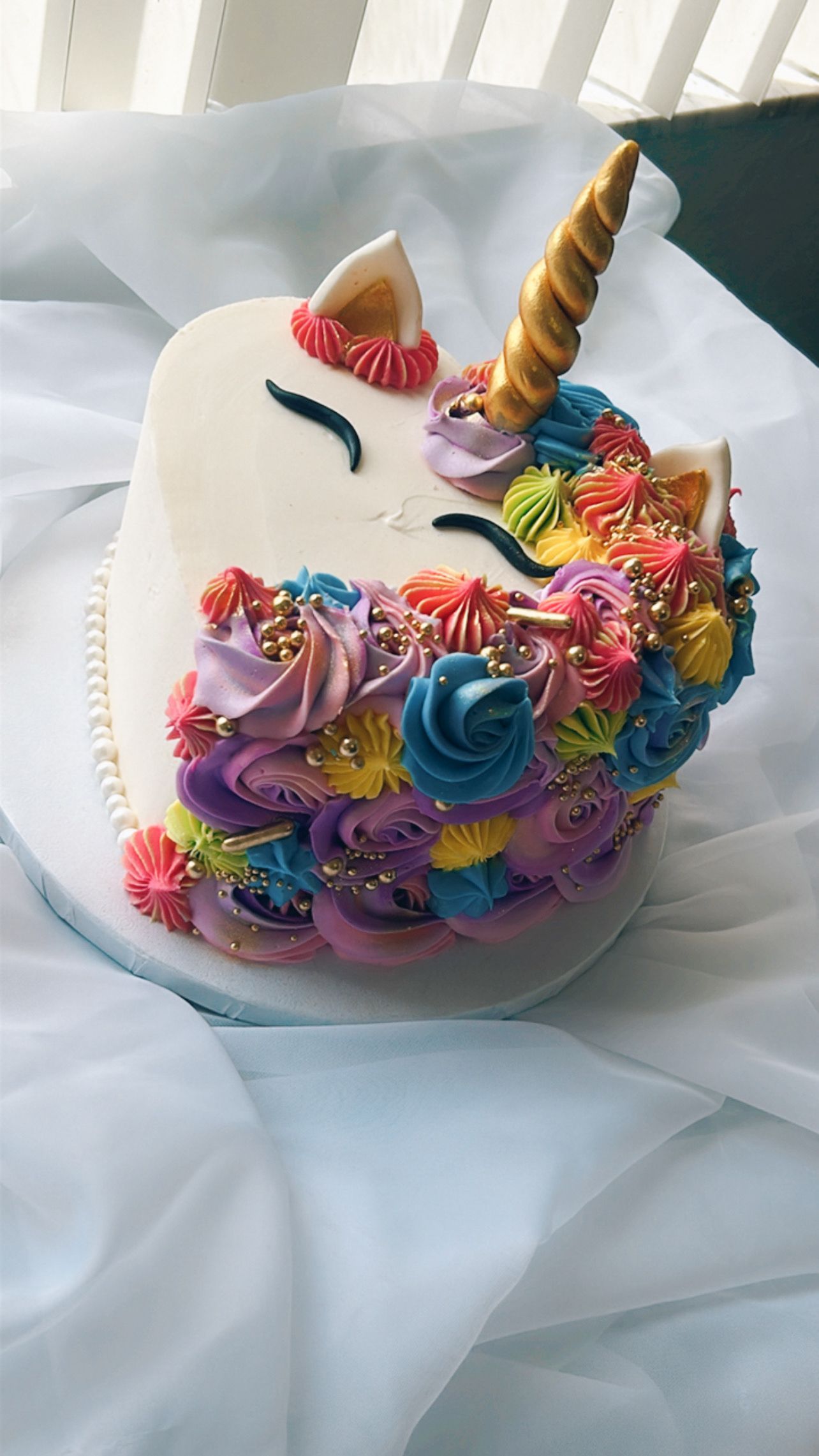A unicorn cake with flowers and sprinkles on it is sitting on a table.