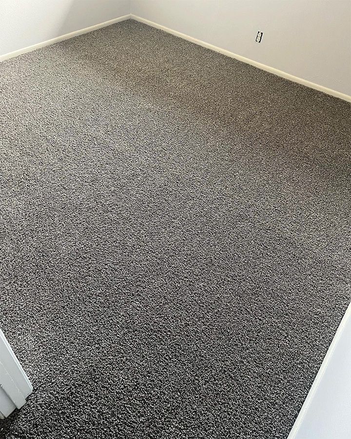 Empty carpeted room with gray speckled floor and white walls