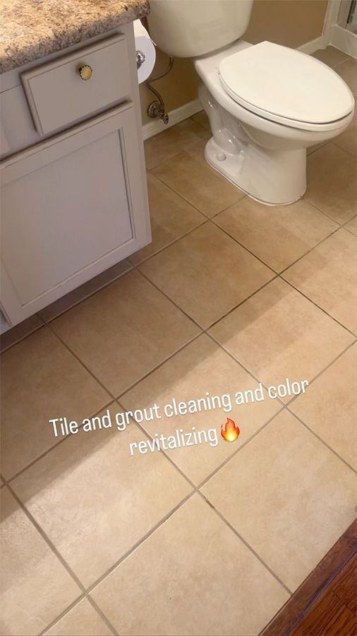 Tiled bathroom floor with a white toilet and vanity cabinet; wet grout cleaning in progress.