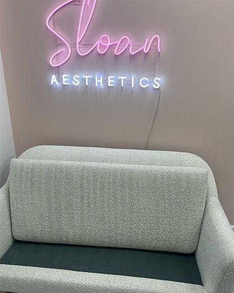 Sloan Aesthetics neon sign above a gray waiting-room chair